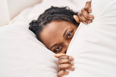 Afrika kökenli Amerikalı kadın yatak odasında yüzünü çarşafla örtüyor.