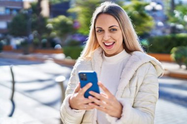 Sokakta akıllı telefon kullanan kendine güvenen genç bir kadın.