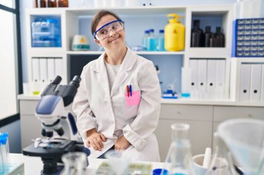 Down sendromlu İspanyol kız bilim adamı laboratuarında çalışıyor. Gülümsüyor ve başka tarafa bakıyor.. 