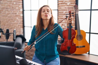 Brunette woman playing violin looking at the camera blowing a kiss being lovely and sexy. love expression. 