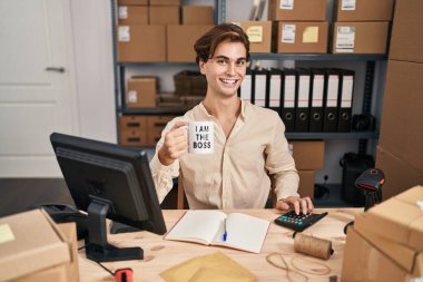 Young caucasian man ecommerce business worker drinking coffee using calculator at office