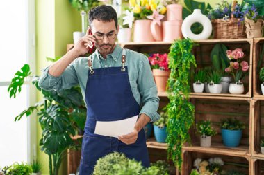 Çiçekçide akıllı telefondan konuşan İspanyol bir çiçekçi.