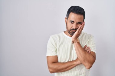 Hispanic man with beard standing over isolated background thinking looking tired and bored with depression problems with crossed arms. 