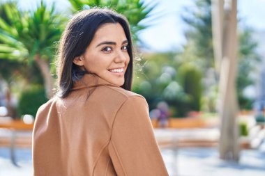 Parkta kendinden emin gülümseyen genç İspanyol kadın.