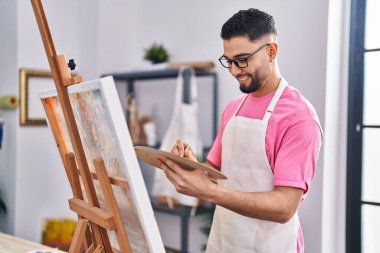 Genç Arap ressam, resim stüdyosunda kendine güvenen bir gülümseme.