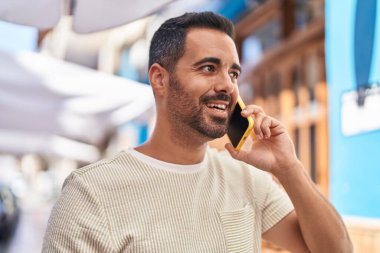 Genç İspanyol adam gülümsüyor. Kendine güveniyor. Sokakta akıllı telefondan konuşuyor.
