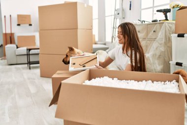 Genç İspanyol kadın yeni evinde köpekle birlikte boks paketini açıyor.