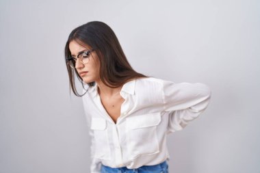 Young brunette woman wearing glasses suffering of backache, touching back with hand, muscular pain 