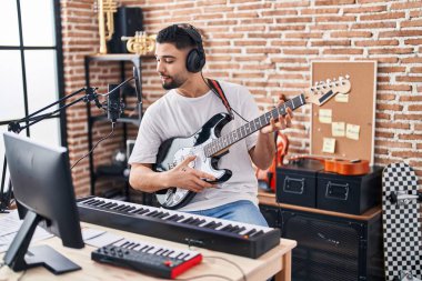 Genç Arap sanatçı müzik stüdyosunda elektro gitar çalarak şarkı söylüyor.