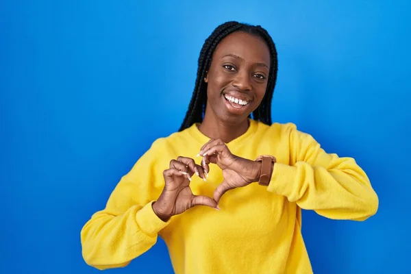 Beautiful Black Woman Standing Blue Background Smiling Love Doing Heart — Zdjęcie stockowe