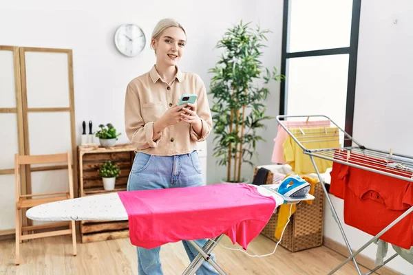 Young Caucasian Woman Using Smartphone Ironing Clothes Laundry Room — Foto de Stock