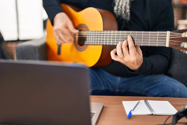 Middle age grey-haired man musician having online classical guitar class at music studio