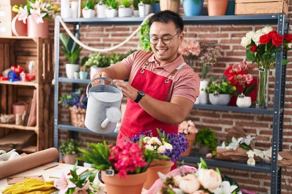 Young chinese man florist watering plant at florist