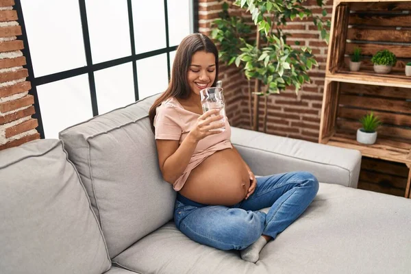 Jonge Latijnse Vrouw Zwanger Drinkwater Zitten Bank Thuis — Stockfoto
