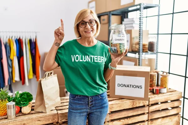 Gönüllü Tişört Giyen Orta Yaşlı Sarışın Kadın Bağış Parası Tutuyor — Stok fotoğraf
