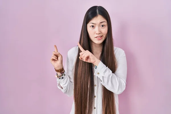 Chinese Jonge Vrouw Staan Roze Achtergrond Wijzen Opzij Bezorgd Nerveus — Stockfoto