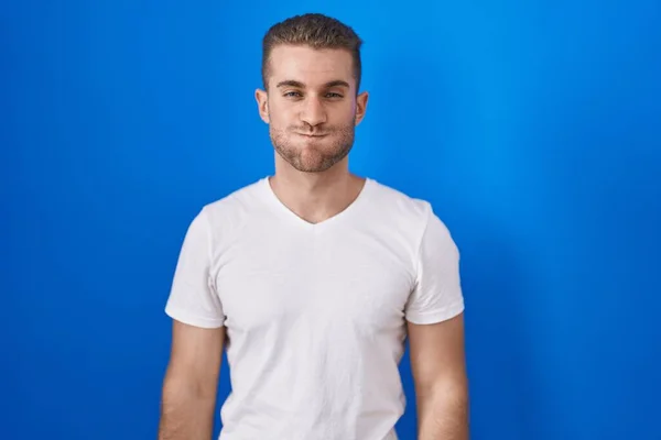 Young Caucasian Man Standing Blue Background Puffing Cheeks Funny Face — Foto de Stock