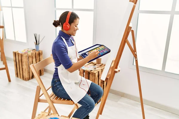 Young latin woman listening to music drawing at art studio
