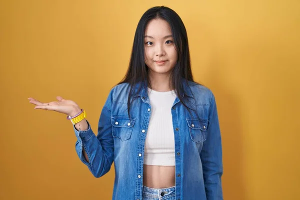 Jonge Aziatische Vrouw Staan Gele Achtergrond Glimlachend Vrolijke Presenteren Wijzen — Stockfoto