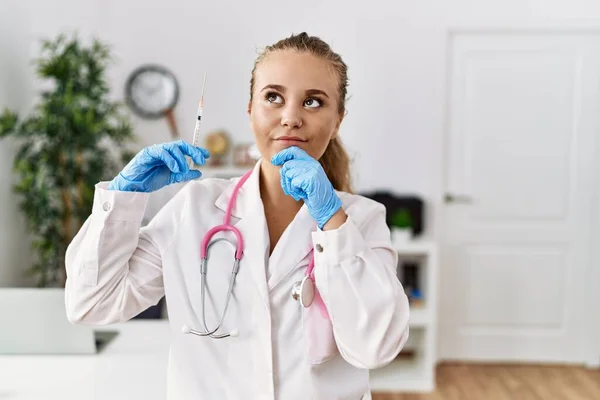 Young Doctor Woman Holding Syringe Clinic Serious Face Thinking Question — Stok fotoğraf