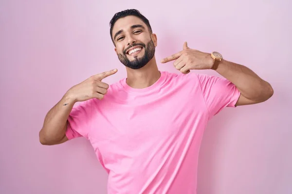 西班牙裔年轻人站在粉红的背景上 笑容满面 用手指 牙齿和嘴指指指点点 牙齿健康概念 — 图库照片