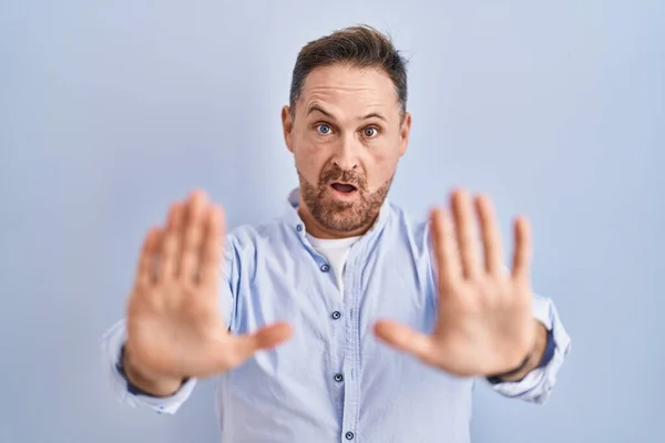 青い背景の上に立っている中世の白人男性手掌で停止ジェスチャーを行います 怒っているとフラストレーション式 — ストック写真