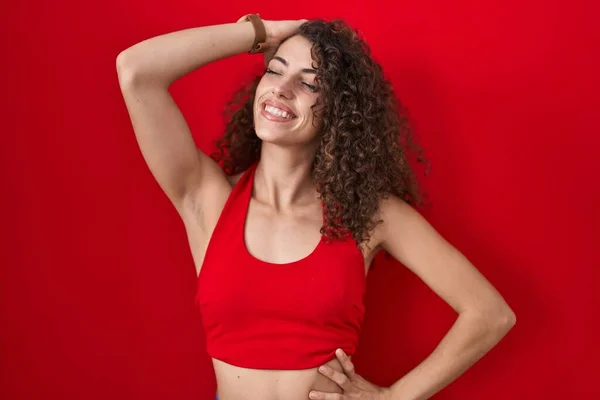 Kırmızı Arka Planda Duran Kıvırcık Saçlı Spanyol Kadın Kendine Güvenen — Stok fotoğraf