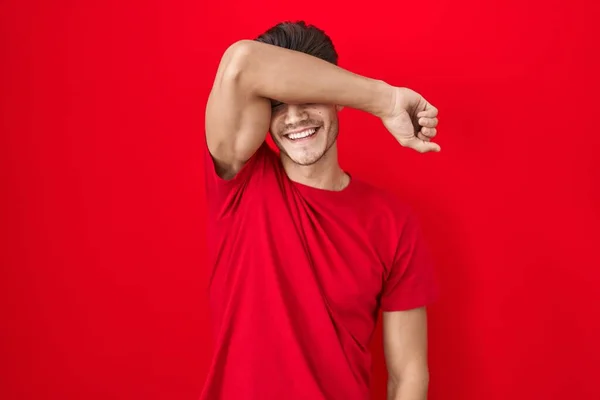Νεαρός Ισπανόφωνος Στέκεται Πάνω Από Κόκκινο Φόντο Καλύπτει Μάτια Χέρι — Φωτογραφία Αρχείου