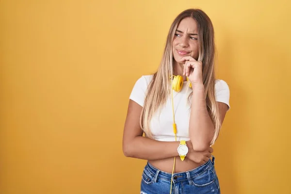 Young Blonde Woman Standing Yellow Background Wearing Headphones Hand Chin — Foto Stock