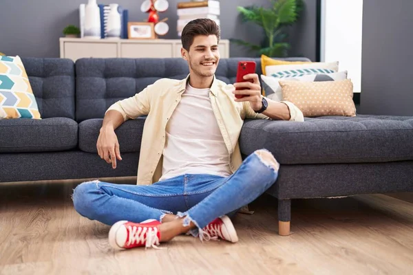 Hombre Hispano Joven Usando Teléfono Inteligente Sentado Suelo Casa —  Fotos de Stock