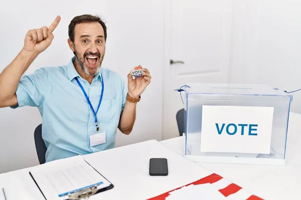 Midaldrende Mand Med Skæg Sidder Ved Afstemning Holder Jeg Stemme - Stock-foto