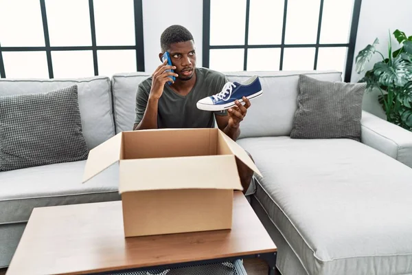 Young African American Man Talking Smartphone Unpacking Sneakers Home — Zdjęcie stockowe