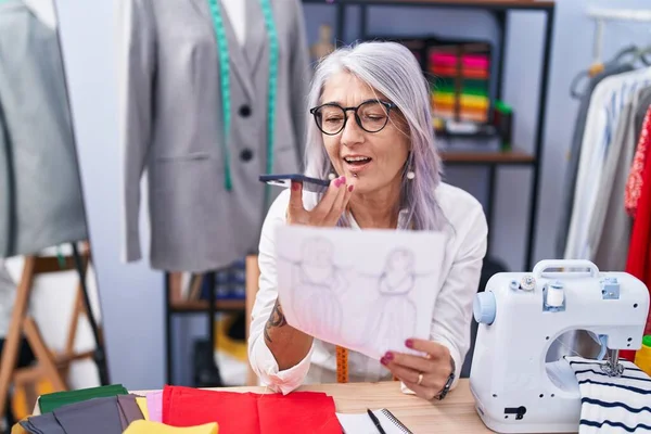 在裁缝店里 中年白发女裁缝在讲智能手机的服装设计 — 图库照片