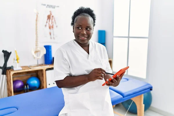 Młoda Afroamerykanka Mundurze Fizjoterapeuty Używająca Touchpada Klinice — Zdjęcie stockowe