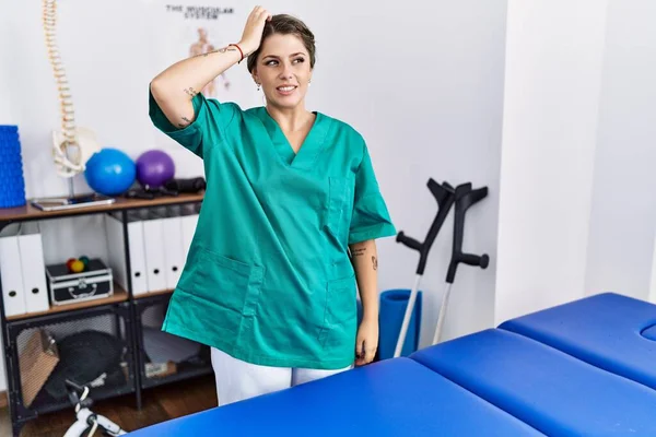 Young Hispanic Woman Wearing Physiotherapist Uniform Standing Clinic Confuse Wonder — Photo