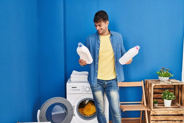 Young Hispanic Man Washing Clothes Holding Detergent Bottles Laundry Room — Stock Photo, Image