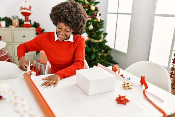 年轻的非洲女人带着自信的笑容在家里包装圣诞礼物 — 图库照片