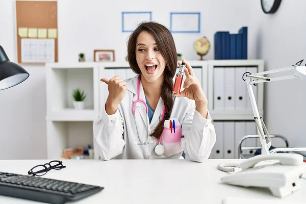 Young Doctor Woman Holding Electronic Cigarette Medical Clinic Pointing Thumb — Stock Photo, Image