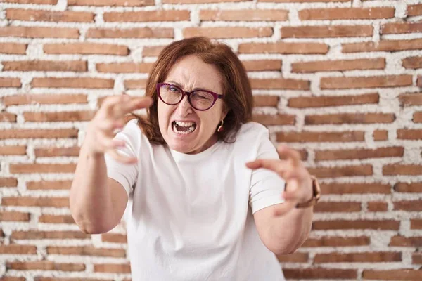Gözlüklü Yaşlı Kadın Tuğla Duvarın Yanında Duruyor Öfkeden Çıldırmış Elleri — Stok fotoğraf