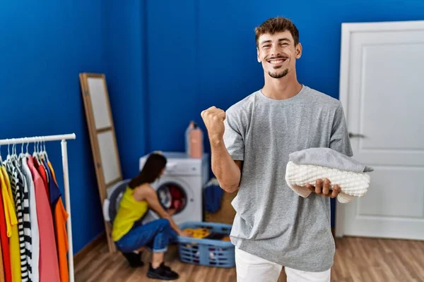 Young Handsome Man Holding Folded Laundry Screaming Proud Celebrating Victory — Fotografia de Stock