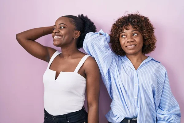 Two African Women Standing Pink Background Smiling Confident Touching Hair — Stok fotoğraf
