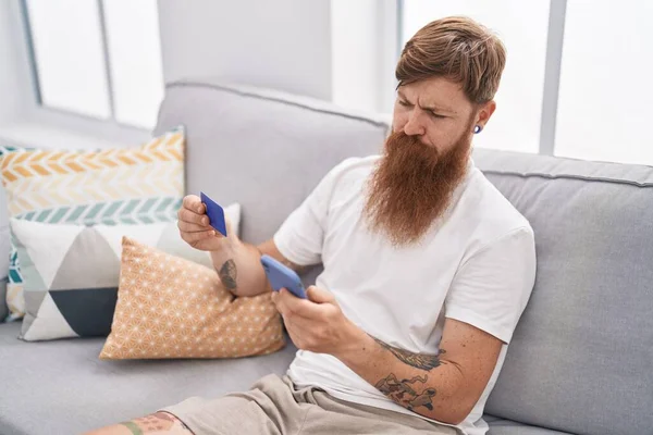 Young Redhead Man Using Smartphone Credit Card Sitting Sofa Home — 图库照片