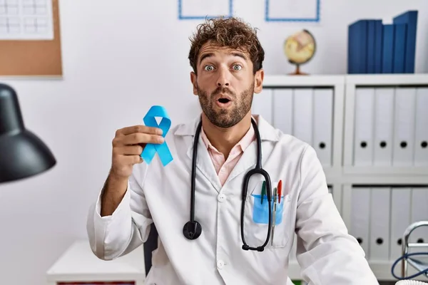 Ung Latinamerikansk Läkare Man Håller Blå Band Rädd Och Förvånad — Stockfoto