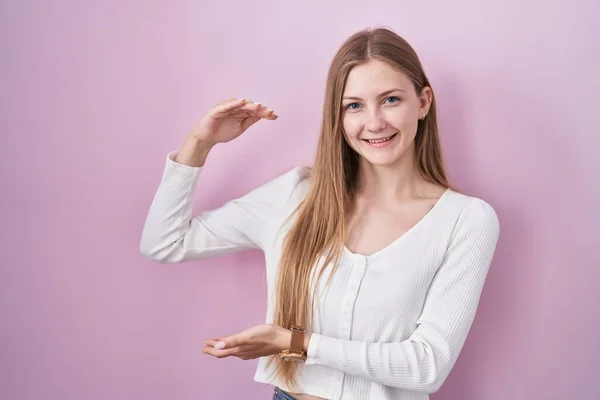 Young Caucasian Woman Standing Pink Background Gesturing Hands Showing Big — Zdjęcie stockowe