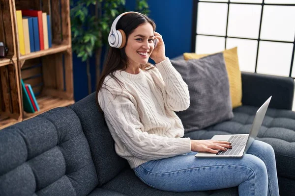 Evdeki Kanepede Oturan Dizüstü Bilgisayar Kulaklık Kullanan Genç Bir Kadın — Stok fotoğraf