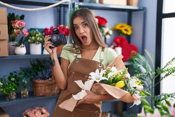 Młoda Brunetka Pracuje Kwiaciarni Trzymając Kamerę Przerażona Zszokowana Zaskakującą Ekspresją — Zdjęcie stockowe