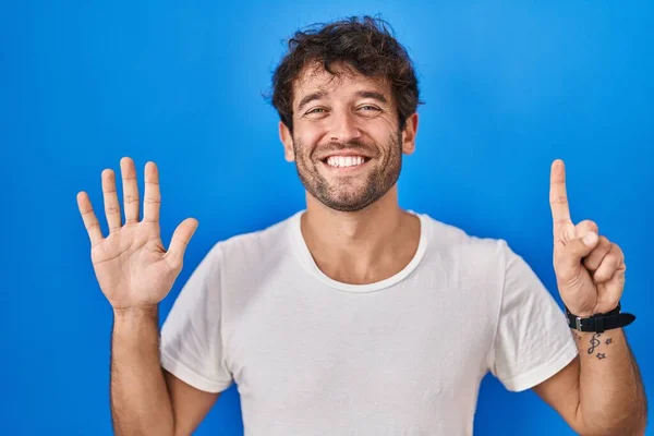 Hispánský Mladý Muž Stojící Nad Modrým Pozadím Ukazující Ukazující Prsty — Stock fotografie