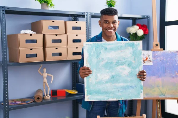Young Hispanic Man Holding Canvas Artist Studio Smiling Laughing Hard — Stok fotoğraf