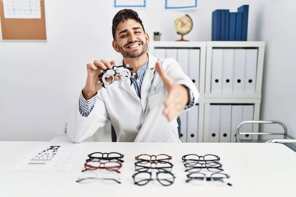 Young Optician Man Holding Optometry Glasses Smiling Friendly Offering Handshake — 图库照片