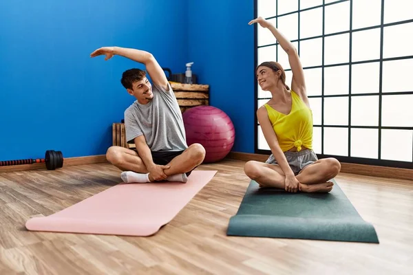 Man and woman couple smiling confident stretching at sport center